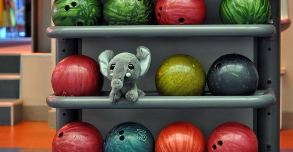 Close-up photography. Toy elephant between bowling balls.
