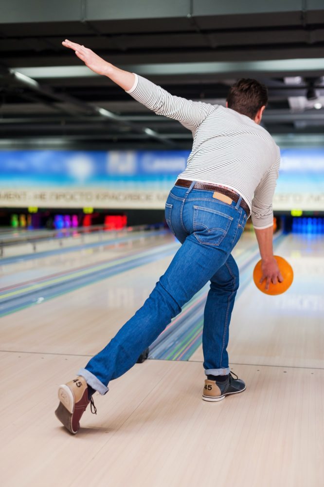 His perfect game. Rear view of young man playing bowling