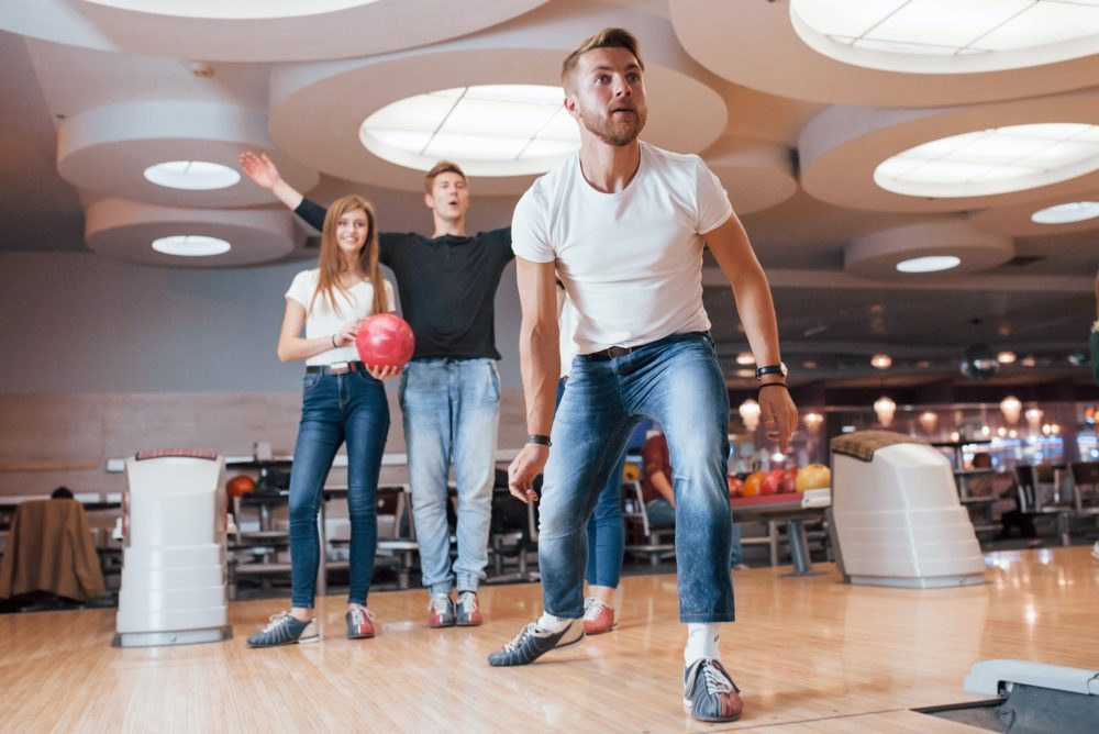 It must be strike. Young cheerful friends have fun in bowling club at their weekends
