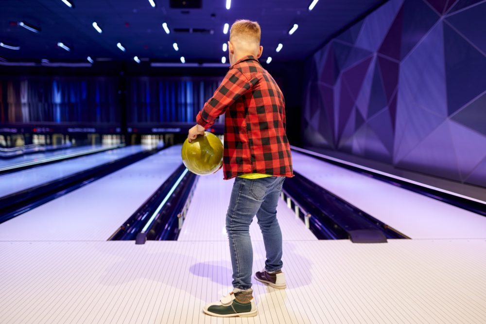 Boy holds a ball at the lane in bowling alley