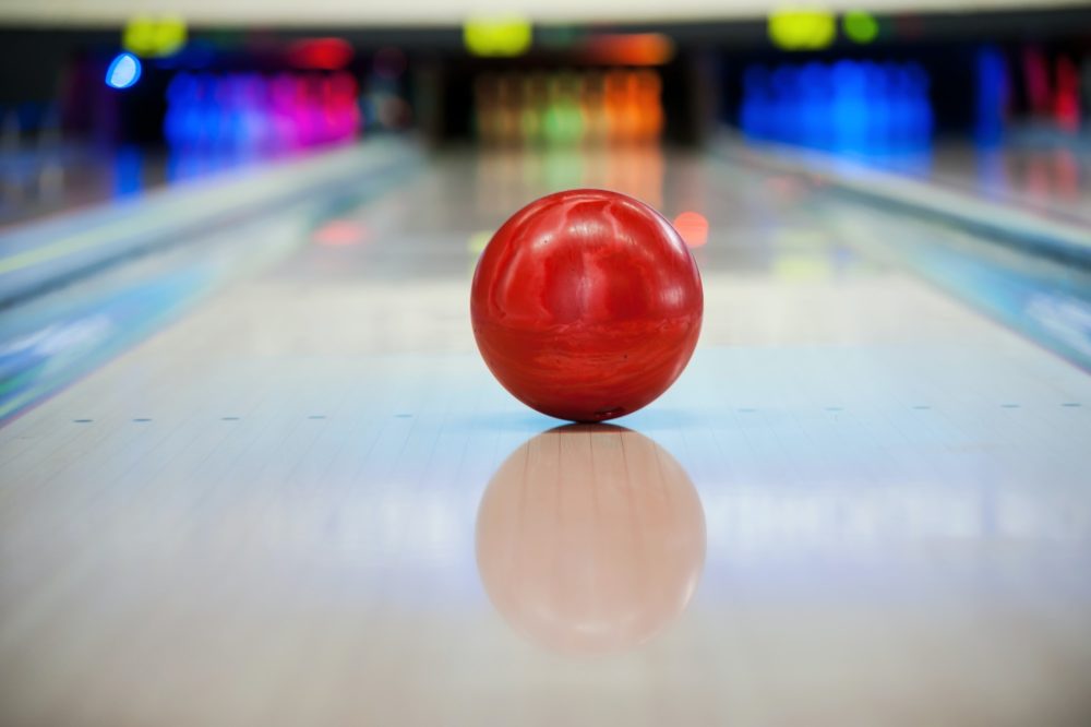 It will be strike! Close-up of bright red bowling ball rolling along bowling alley