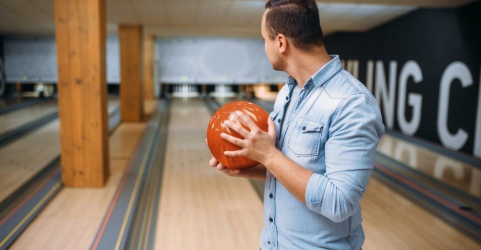 Male bowler standing on bowling lane and poses with ball