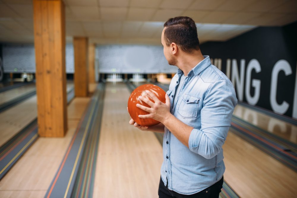 Male bowler standing on lane and poses with ball