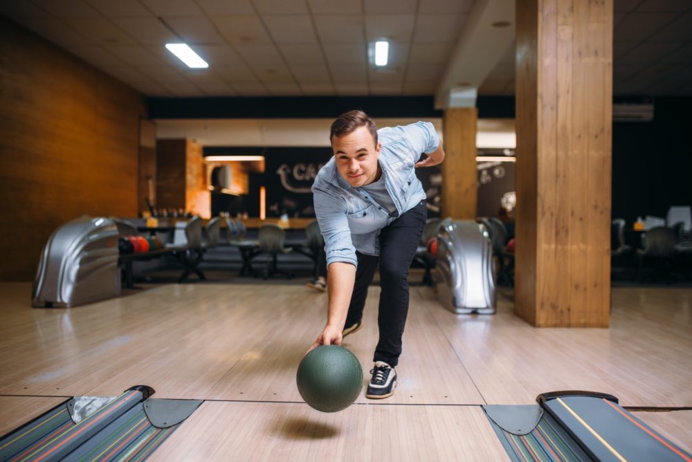 Male bowler throws ball on lane, front view