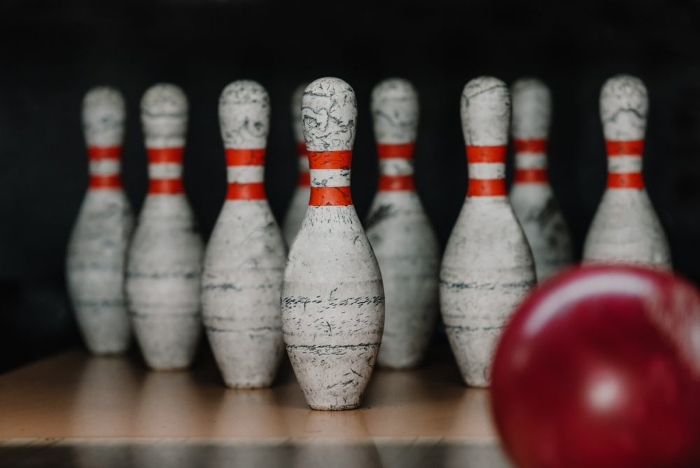 close-up shot of grungy bowling pins with red ball on foreground