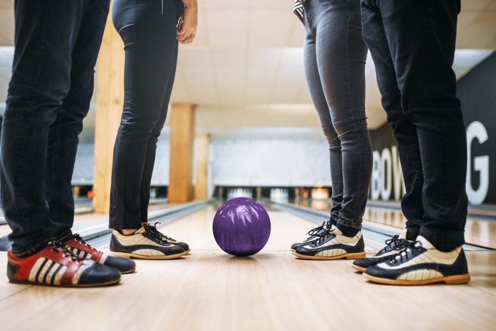 Bowling team, feet in house shoes and ball on lane