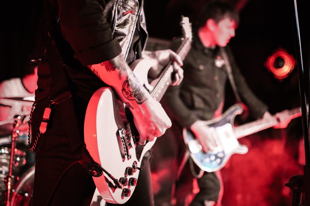 Punk rock band guitarists playing live on stage in concert