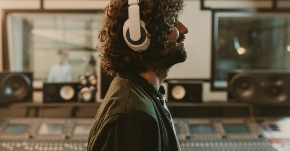 side view of sound producer in headphones enjoying music at studio