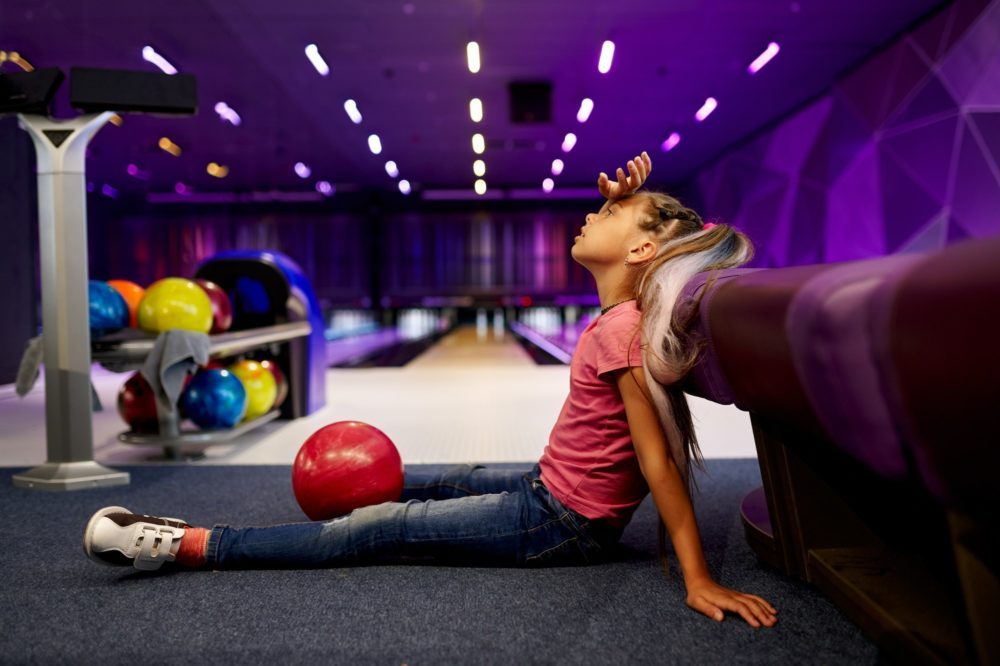 Girl sitting on the floor in bowling alley