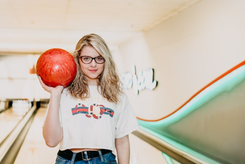 A girl with blonde hair holding a bowling ball