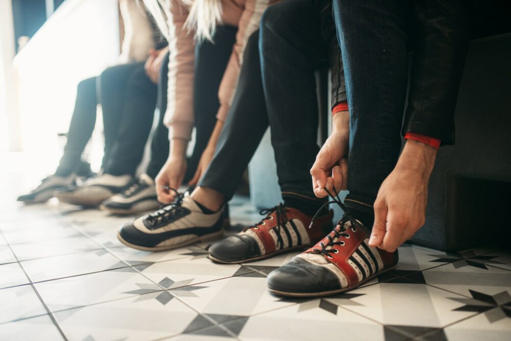 Bowling players ties shoelaces on house shoes